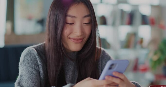 Young asian attractive woman reading good news in mobilw phone enjoying fun communicating with friends chatting messages on social media at home.