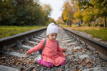 little girl sitting on the railroad tracks