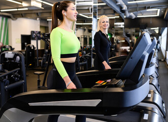 Beautiful smiling athletic woman doing fitness cardio exercises in the gym, running on a treadmill....