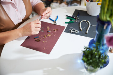 Female jeweler making gold earrings in her workshop