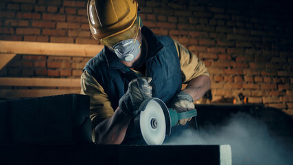 Male builder in respirator using angle grinder