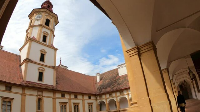 A woman in a black leather jacket enjoying the view on the bell tower of Eggenberg castle in Graz, Austria. while walking around the cloister. There is a square patio in the middle part. Appreciation

