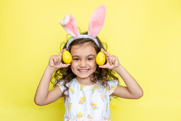 funny happy child girl with easter eggs on yellow background