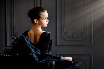 Fototapeta na wymiar Portrait of young ballerina girl in black tutu on dark background