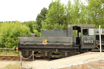 Fototapeta na wymiar Steam locomotive full of coal running on a track through the countryside 