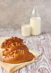Breakfast concept, homemade pies and milk on wooden table, close up