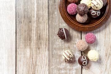 Chocolates candy on a plate on a wooden table. Cutaway candy, two halves. View from above....