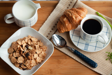 Healthy breakfast in bed served tray in bed with cornflakes and dried fruits and a cup of coffee with croissant. Good start to the day to have the right meal.