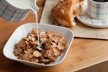Healthy breakfast in bed served tray in bed with cornflakes and dried fruits and a cup of coffee with croissant. Good start to the day to have the right meal.