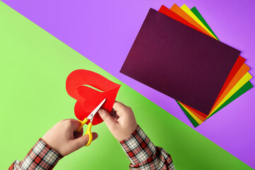 Children's hands cut the applique on a two-color table with scissors.