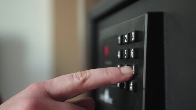 Close-up of hand opening metal safe box with pass code in the hotel room.