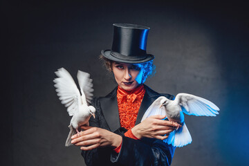 Circus female perfomer poses in dark background holding two doves