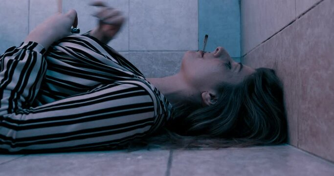 Pensive girl lying on the ground smoking