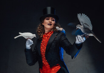 Spectacular female conjurer in dark background with spotlight and doves