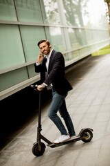 Young businessman using mobile phone  on electric scooter