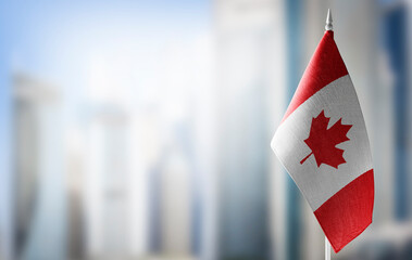 A small flag of Canada on the background of a blurred background