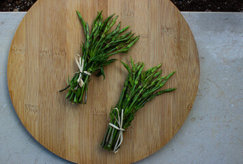 Hop buds, Humulus lupulus, also called Bruscandoli, collected in bunches on a round wooden cutting board. Used for tasty Italian dishes.