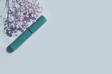 mascara, gypsophila flower on colored background