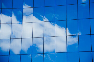 clouds reflected in windows of modern office building