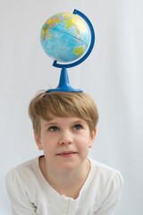 The child is holding a globe on his head in balance. The concept of the dependence of the earth on the future generation