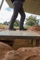 Visitor crossing above the famous Atlantis stele of Cancho Roano. Extremadura, Spain