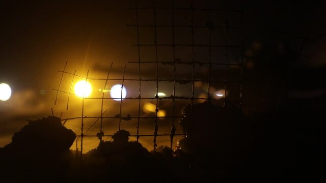 War Concept. Armored vehicle silhouette fighting scene on war foggy sky background at night. American tank moving in destroyed city. Slider shot
