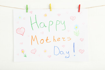 Text Happy Mothers Day with clothespins hanging on white wooden background