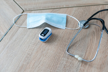 A blue phonendoscope is on the table with a blue pulse oximeter