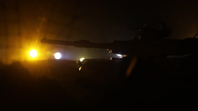 War Concept. Armored vehicle silhouette fighting scene on war foggy sky background at night. American tank moving in destroyed city. Slider shot