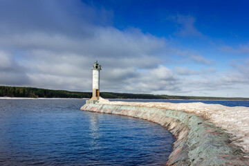 Obraz premium A lighthouse in sunny weather. Lighthouse on the breakwater. Lighthouse on the lake.