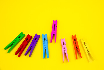 Colorful wooden clothespins on yellow background. Close up, copy space. Minimalism, original and creative photo. Be another. Individuality concept.