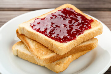 Toasts with raspberry jam in plate on wooden table