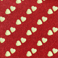 Diagonal pattern of pairs of hearts made of light yellow stone on a red background.