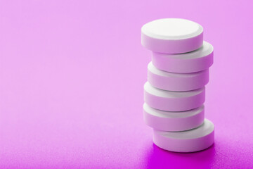 White Ecstasy pills in a row on a pink background, isolate.