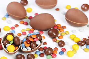 Easter chocolate eggs with candies on white wooden table