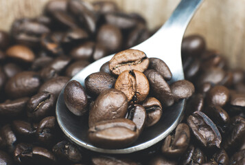 Roasted coffee beans in the wooden pot. Close up, macro photo.