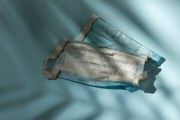 Dirty used protective mask on background with shadow