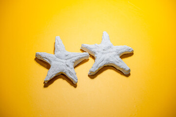 Fototapeta na wymiar Pair of the plaster starfishes on yellow background.