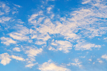 Blue sunny sky with white contrasting clouds for background