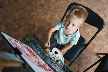 Little boy draw a picture on an easel