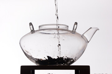Silhouette of water pouring in clear glass teapot on white background
