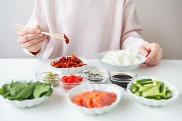 The process of preparing sushi, preparing all the ingredients for the sushi, the girl is holding the chopsticks.