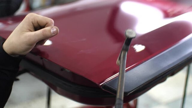 PDR. Paintless Dent Repair Removal. Close-up hammer, which knock on the red car to align dents without painting and fix it. High quality 4k footage