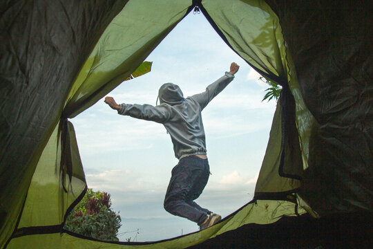 Hombre acampando en una carpa y dando un salto de alegr&iacute;a fuera de su  tienda de campa&ntilde;a