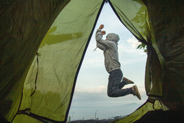 Hombre acampando en una carpa y dando un salto de alegría fuera de su  tienda de campaña