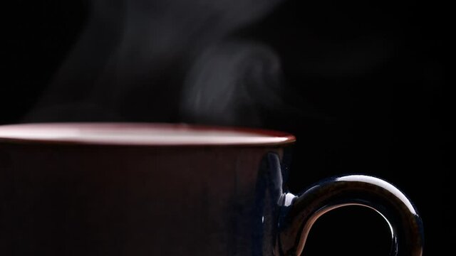 Coffee cup with natural steam smoke of coffee on wooden table, black background with copy space, slow motion. Hot Coffee Drink Concept.