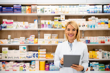 Portrait of smiling female caucasian pharmacist standing in drug store holding tablet computer.