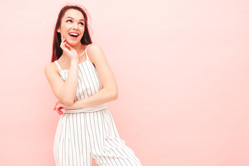 Portrait of young beautiful smiling female in trendy summer hipster overalls clothes. Sexy carefree woman posing near pink wall in studio. Positive model having fun indoors. Cheerful and happy