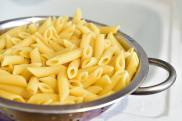 Freshly washed Italian pasta in a colander in the kitchen