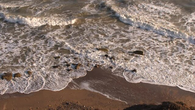 Aerial Drone Footage Of Crashing Waves And Sunset Hitting The Beach Bright Day